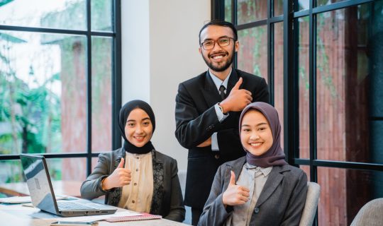 business team showing thumb up while sitting at the office